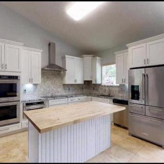A modern kitchen with white cabinetry, a central island, and stainless steel appliances.
