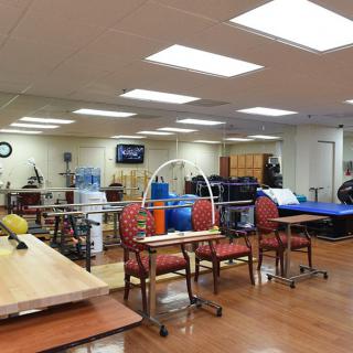 A well-equipped physical therapy and rehabilitation room with various exercise machines and equipment.