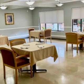 An empty dining room with neatly arranged tables and chairs, featuring soft indoor lighting and large windows.