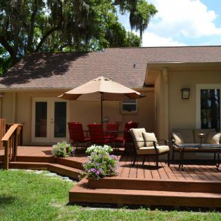 A cozy backyard patio with a wooden deck and outdoor furniture under a large umbrella.