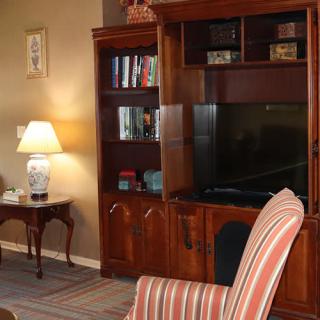 A cozy living room with a wooden bookshelf, television, and striped armchair.