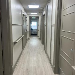 A well-lit, spacious hallway with uniform doors on both sides.