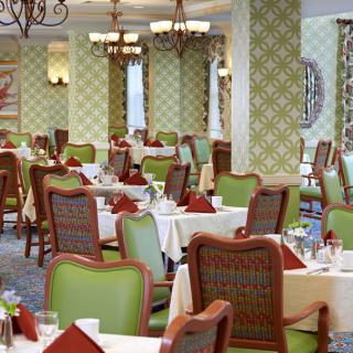 A well-decorated dining room with neatly arranged tables and chairs, featuring elegant interior design and lighting.