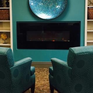 A cozy living room with turquoise armchairs facing a modern fireplace.