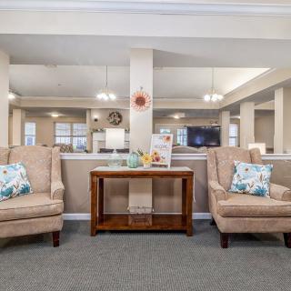 A cozy living room area with two upholstered chairs and a wooden table, adorned with decorative pillows and various decor pieces.