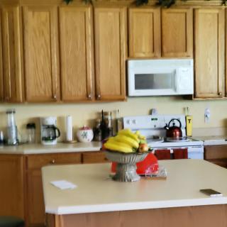 A cozy kitchen with wooden cabinets, a countertop featuring a microwave, and a fruit bowl filled with bananas.