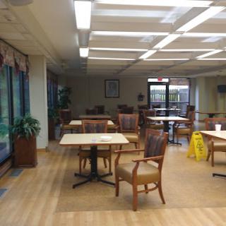 A spacious dining area featuring tables and chairs, illuminated by natural light.