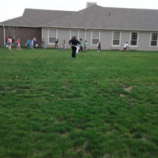 Children enjoying outdoor playtime in a grassy area near a building.