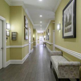 A well-lit hallway featuring framed artwork, cushioned benches, and decorative wall sconces.
