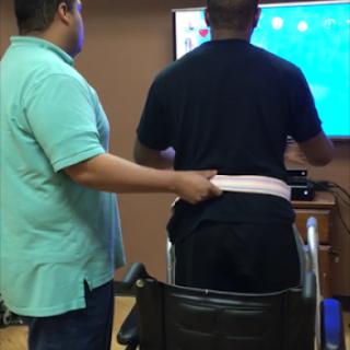 A therapist assisting a patient in using gaming technology for rehabilitation.