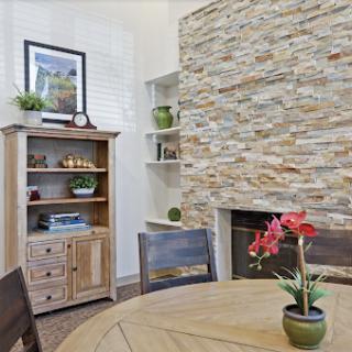 A cozy living area featuring a stone accent wall, wooden furniture, and decorative plants.