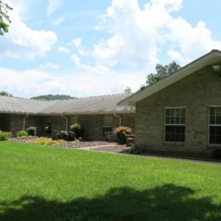 A suburban brick house with a well-maintained lawn under a clear blue sky.