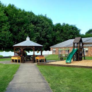A vibrant playground area featuring a gazebo and slide, set in a spacious green lawn.