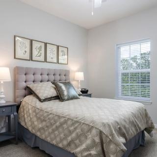 A cozy and well-decorated bedroom with a tufted headboard, elegant bedding, and framed artwork on the wall.