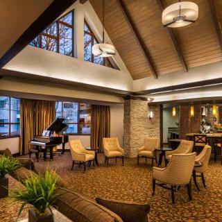 A cozy lounge area with a grand piano and comfortable seating, featuring modern decor and warm lighting.