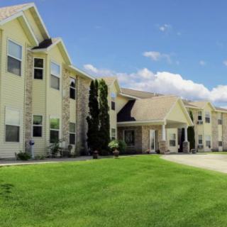 A two-story residential building with a well-maintained lawn and clear blue sky.