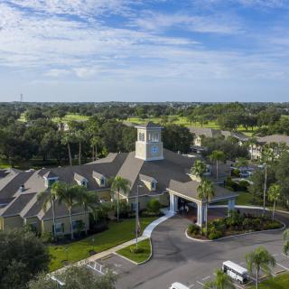 An aerial view of a large building surrounded by greenery and a clear blue sky.