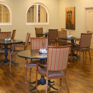 An empty dining area with tables and chairs on a wooden floor.