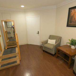 A cozy hallway with a mirror, stairs, and a comfortable chair next to a small table.