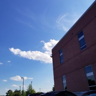 A clear blue sky with fluffy clouds beside a brick building.