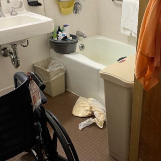 An accessible bathroom with a wheelchair, sink, and bathtub.