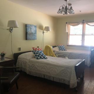 A cozy bedroom with two twin beds, elegant lighting, and a window letting in natural light.