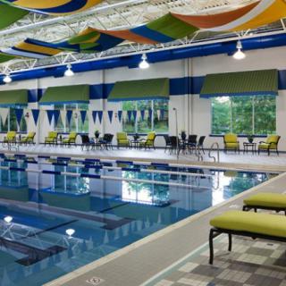 A relaxing indoor swimming pool area with colorful ceiling decorations and poolside seating.