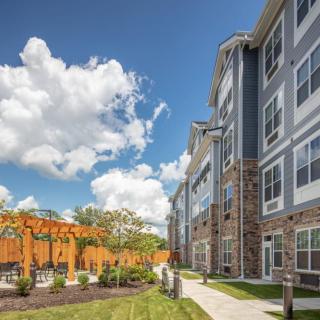 Modern apartment building with landscaped gardens and a clear blue sky.
