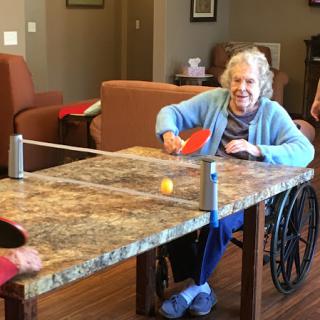 Residents enjoying a fun game of table tennis in a care facility.