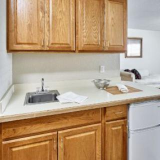A small kitchen area with wooden cabinets and white countertop.