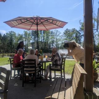 A cheerful outdoor gathering under the umbrella, enjoying a sunny day.