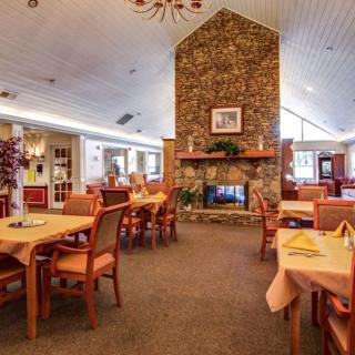 A cozy dining area with a central fireplace, surrounded by neatly arranged tables and chairs.