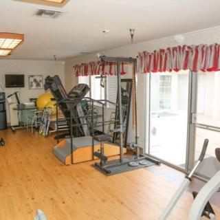 A well-equipped home gym featuring a treadmill, stationary bike, and other exercise machines with ample natural light.