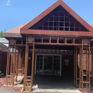 A striking modern wooden structure with a triangular roof, designed to create an inviting entrance.