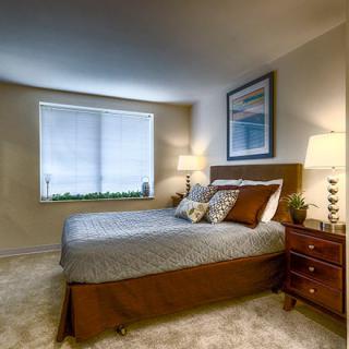 A cozy bedroom with a neatly made bed, two lamps, and a nightstand.