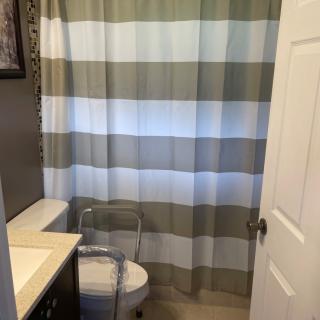 A modern bathroom featuring a striped shower curtain, toilet, and sink.