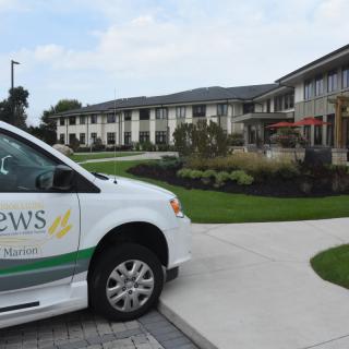A van parked in front of a modern building with landscaped greenery.
