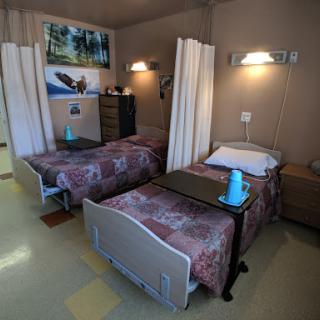 A shared hospital patient room featuring two beds, separated by curtains for privacy.
