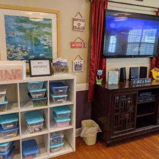 A well-organized classroom corner with storage bins and a television for educational purposes.