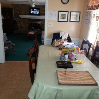A dining area with a table covered in various items, connected to a living space.