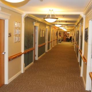 A well-lit, carpeted hallway with multiple doors and wall-mounted lights.