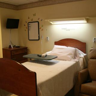 A clean and organized hospital room with a bed, side table, and recliner chair.