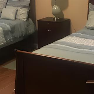 A cozy bedroom featuring two neatly made beds with a nightstand and lamp in between.