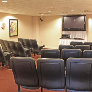 A small conference room with rows of seats facing a television.
