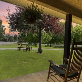 A cozy porch with a rocking chair overlooking a serene lawn at sunset.