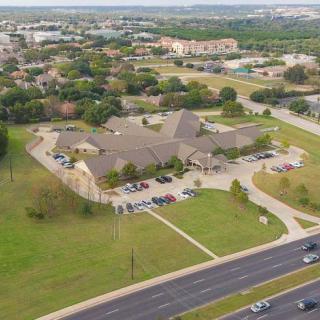 Aerial view of a suburban area with a large building complex and surrounding green spaces.