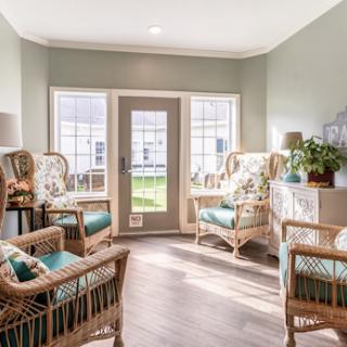 A bright and cozy seating area featuring rattan chairs and green walls, perfect for a relaxing afternoon.