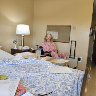 A patient sits comfortably in a hospital room, surrounded by personal items and a warm lamp lighting the space.