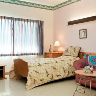 A cozy bedroom with a single bed, bedside lamp, and decorative curtains.