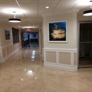 A well-lit hallway featuring artwork on the walls and polished flooring.